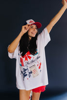 Woman wearing a white graphic t-shirt and red shorts with a dark background