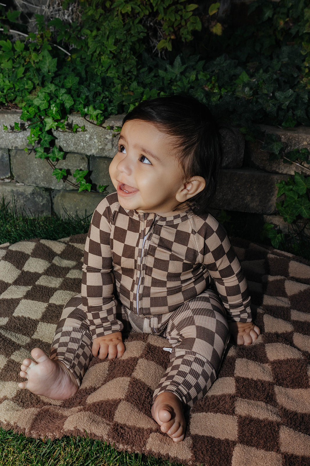Baby in the brown check zip pajamas on the matching blanket.