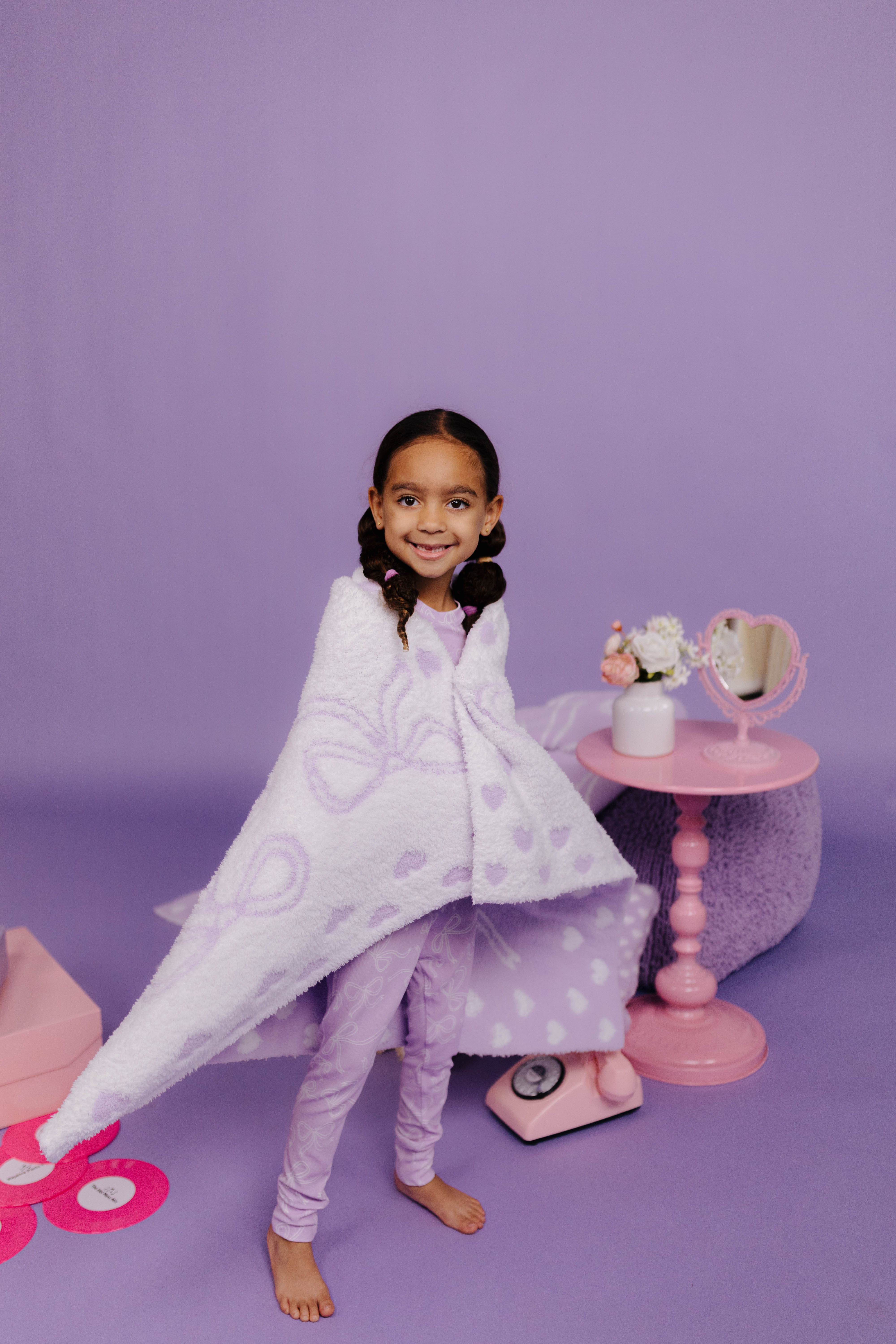 child wrapped in purple and white bow blanket