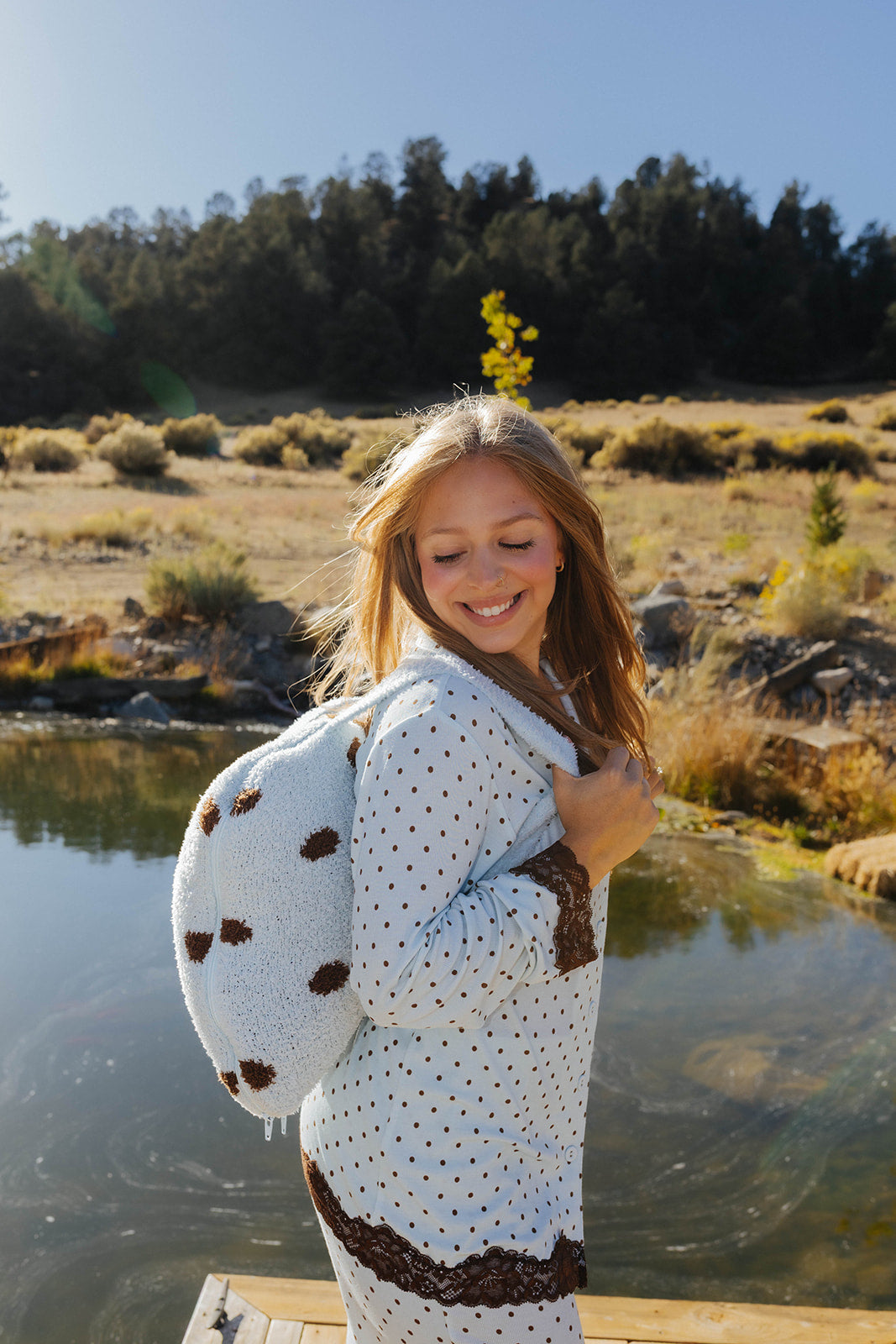 Model carrying the light blue and brown polka dot quillow as a backpack.