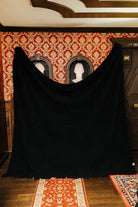 Black waffle fringe blanket held open to show its full size
