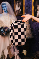 Sand and black check cosmetic bag held in front by its top handle