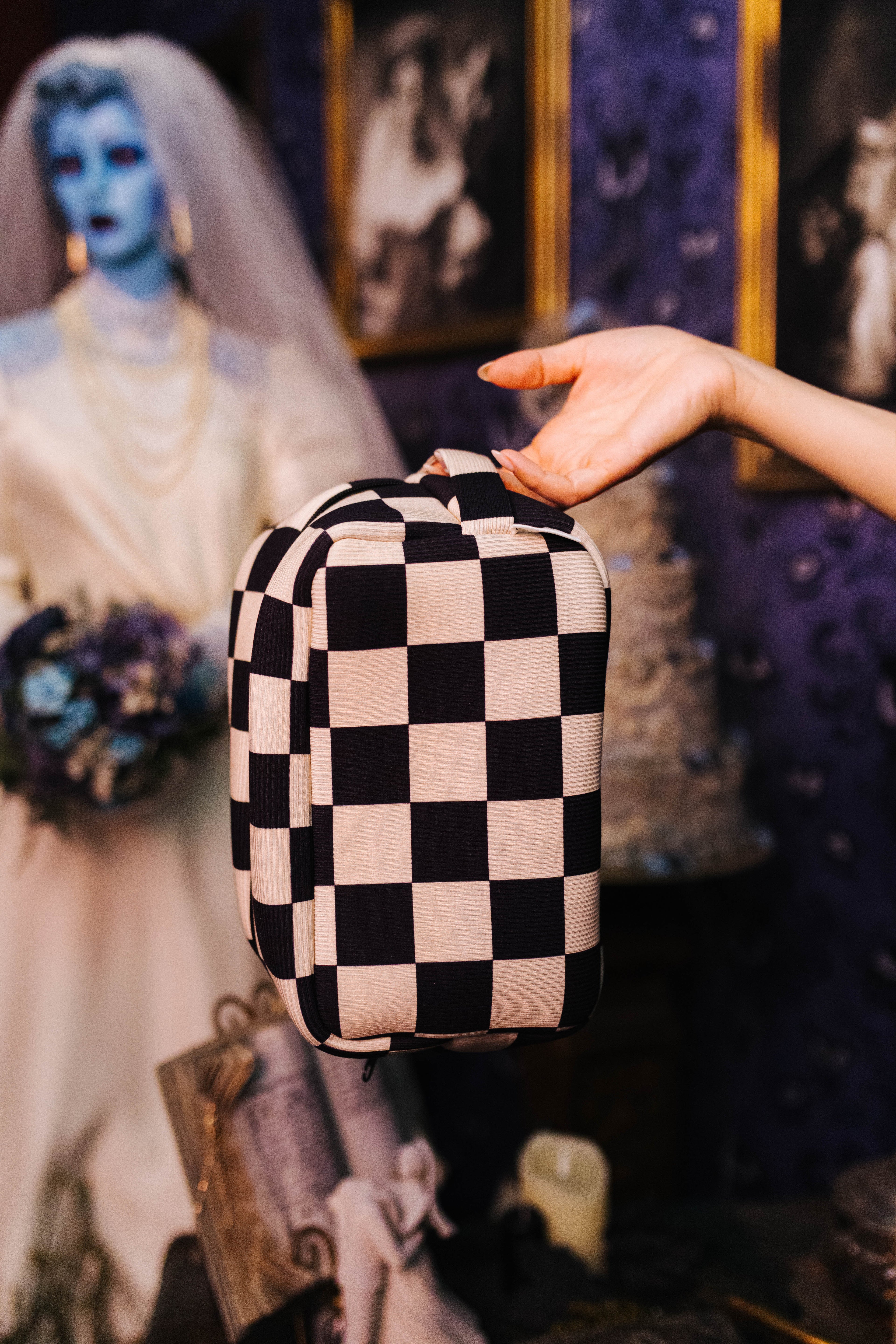 Sand and black check cosmetic bag held in front by its top handle