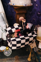 Open sand and black check cosmetic bag filled with makeup