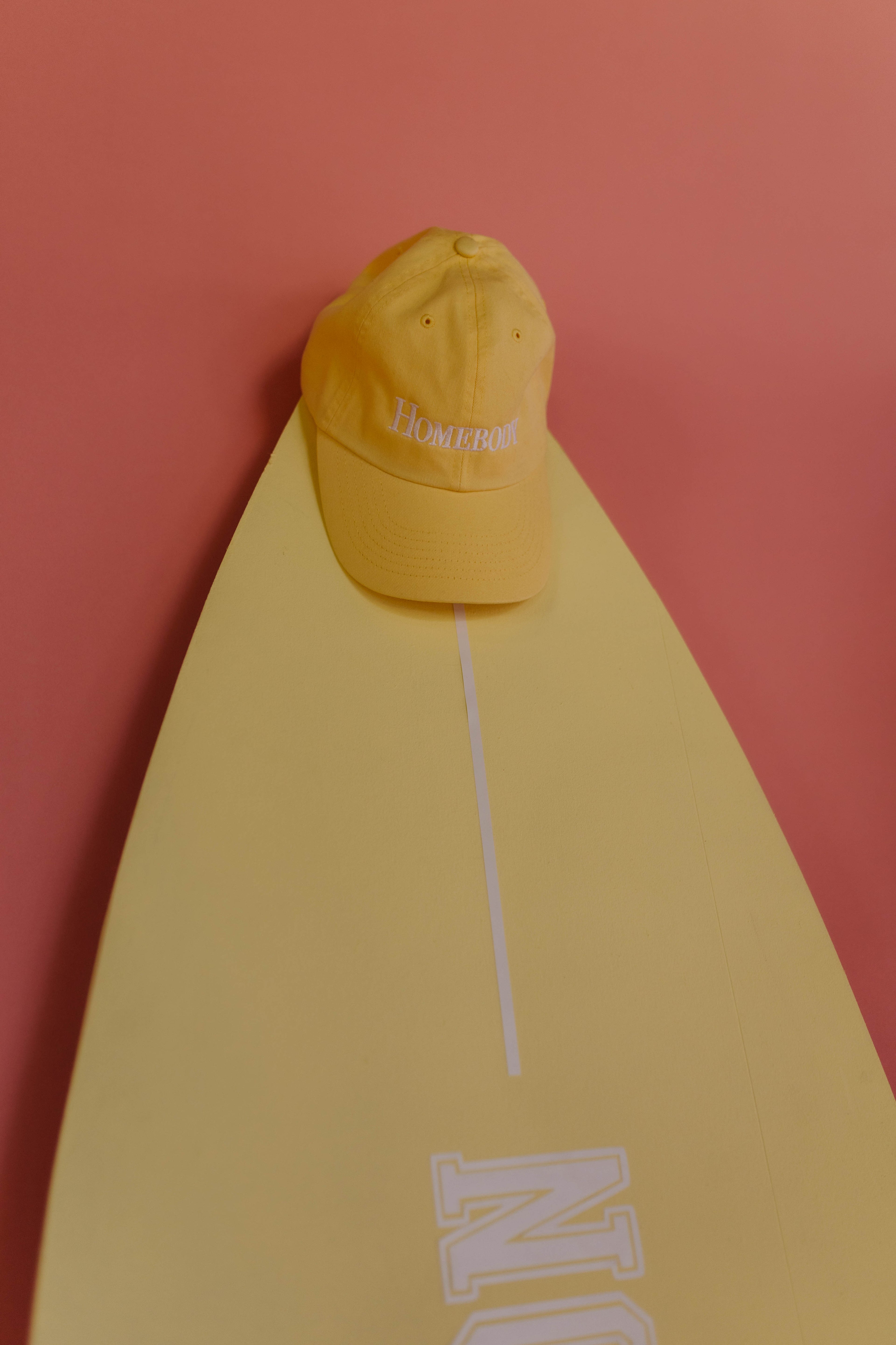 Yellow hat on a yellow surfboard with a pink background