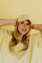 Woman wearing a yellow hat and shirt against a yellow background