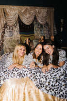 Three models sharing a leopard faux fur blanket