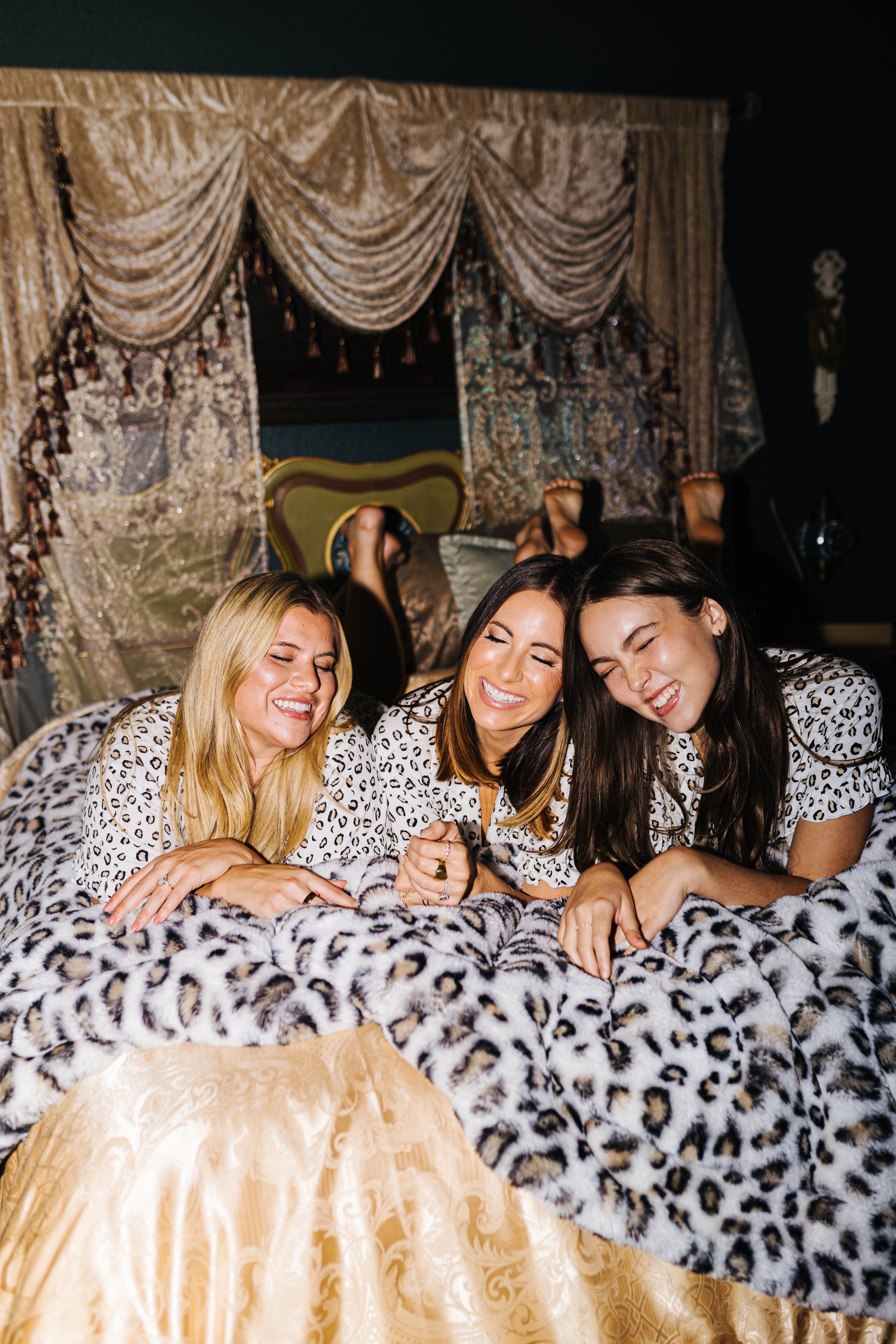 Three models sharing a leopard faux fur blanket