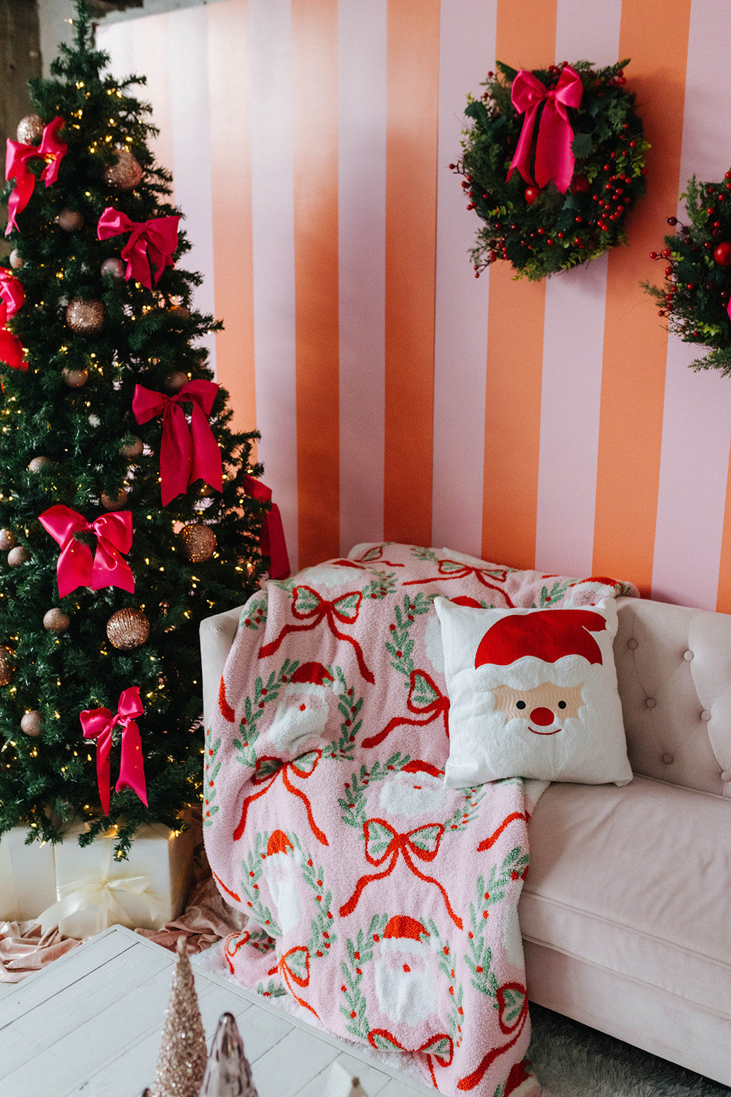 Living room with Christmas tree, wreaths, and festive decor against a striped wall.