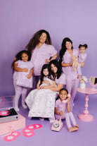 Models posing together in matching lavender outfits on a purple background