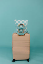 Beige suitcase with a checkered quillow on a teal background
