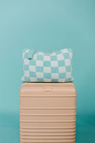Checkered teal quillow on a beige suitcase