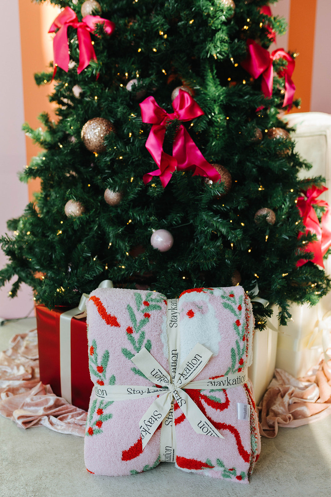 Decorated Christmas tree with pink ribbons and a wrapped gift in front.