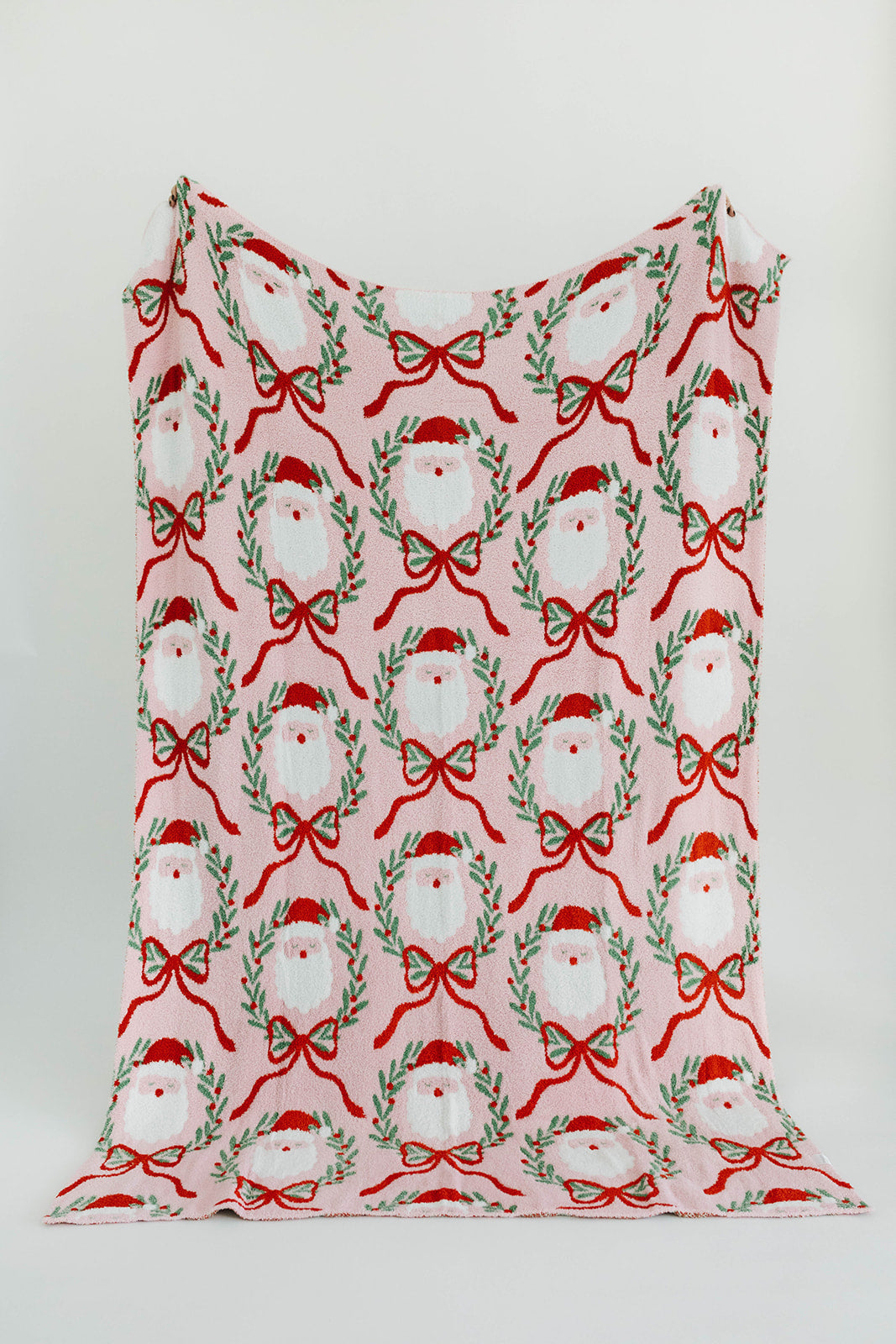 Fabric with Christmas-themed pattern featuring Santa hats, wreaths, and bows on a white background