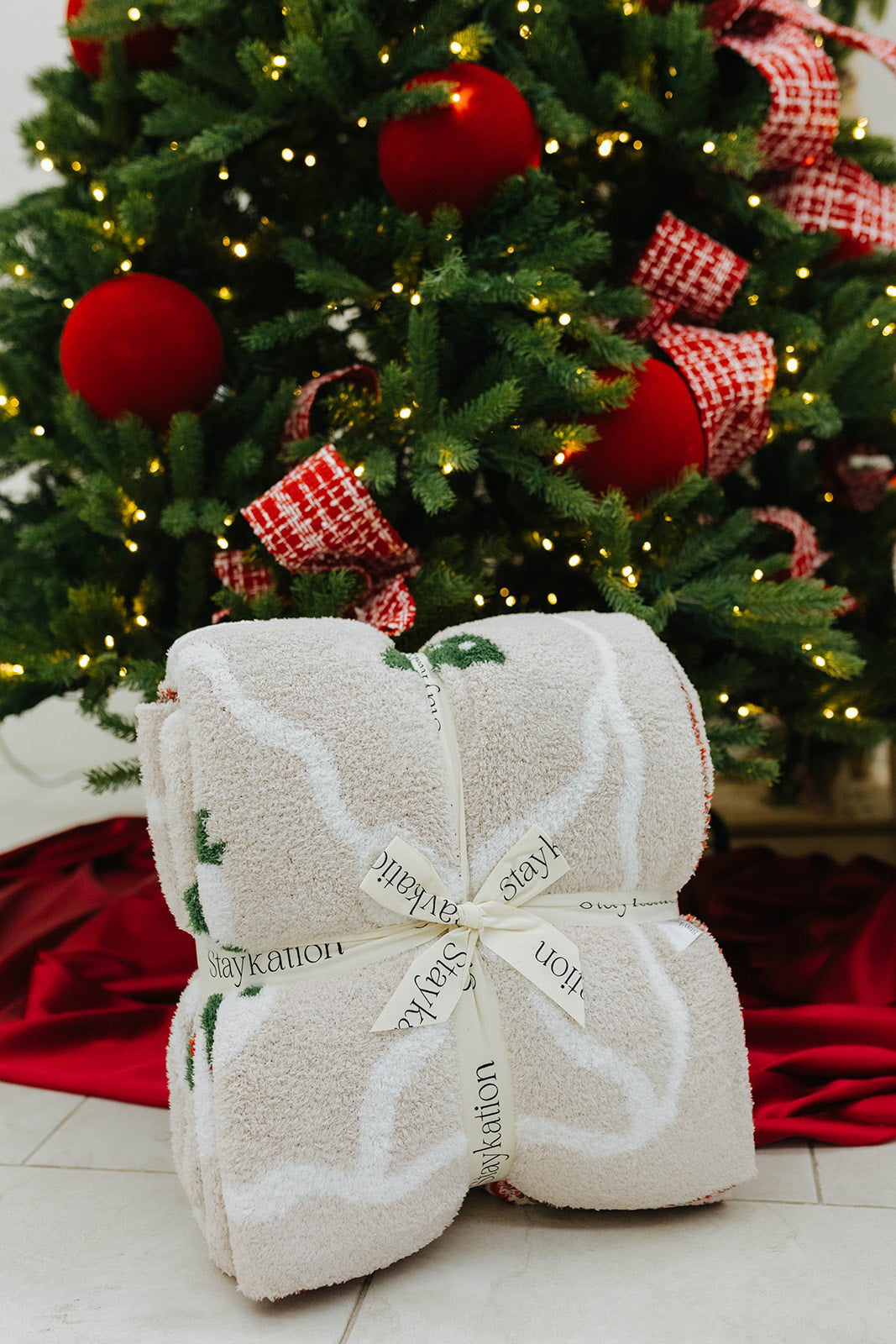 Folded blanket with text in front of a decorated Christmas tree