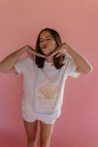 Woman wearing a white t-shirt with a graphic design on a pink background