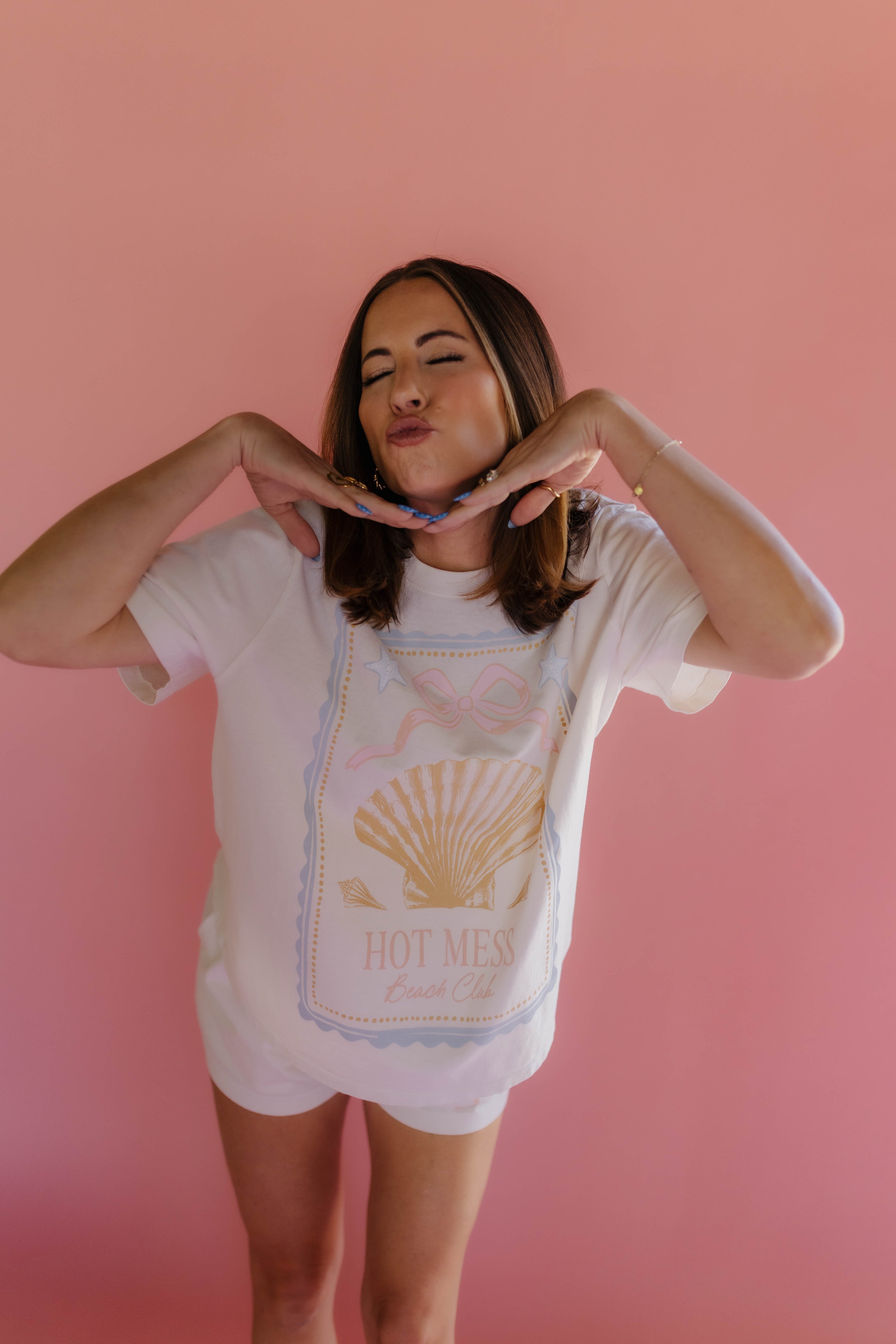 Woman wearing a white t-shirt with a graphic design on a pink background