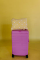 polka dot quillow on pink suitcase sitting on top of it