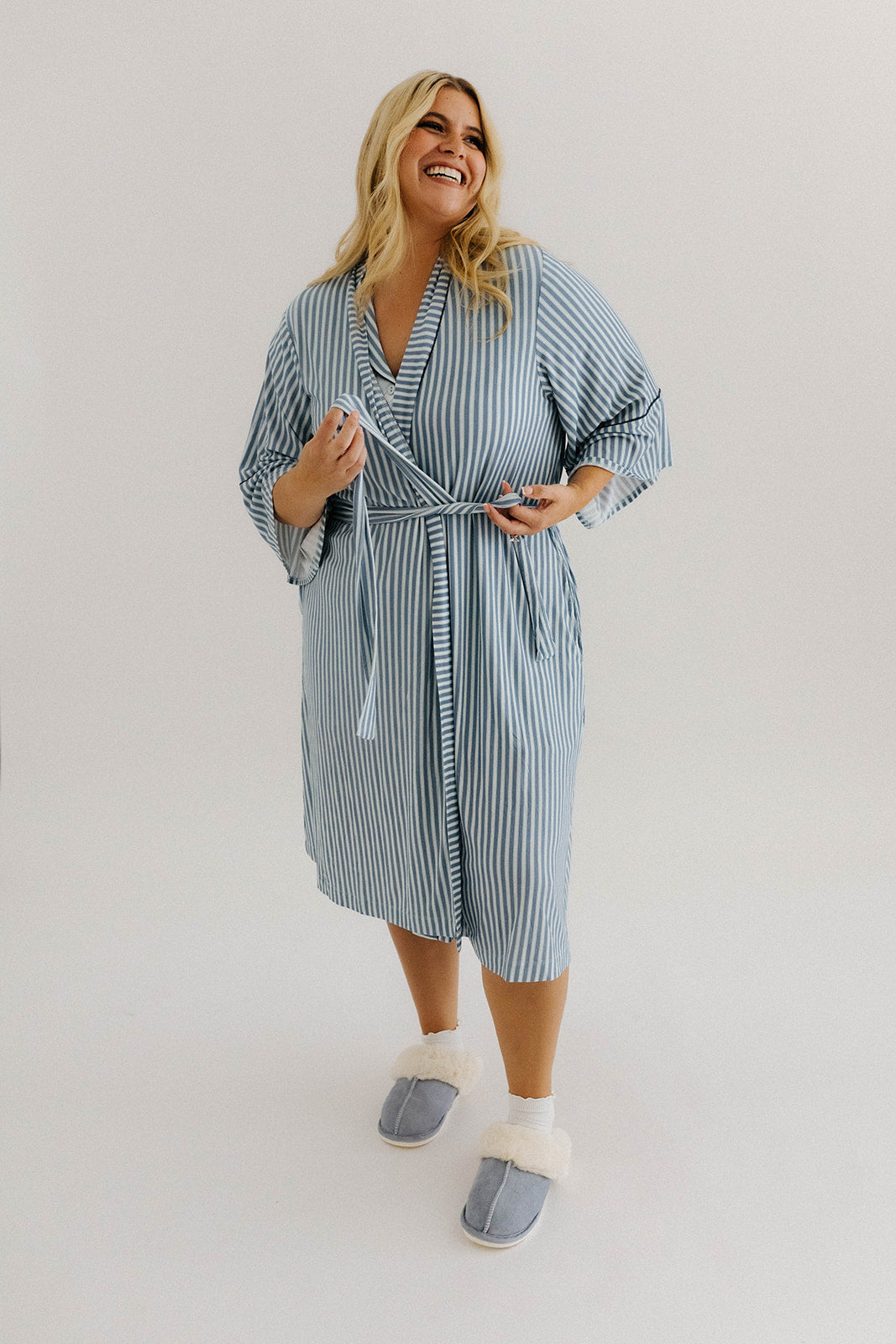 model smiling tying the ties of the blue striped robe 