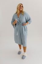 model smiling tying the ties of the blue striped robe 