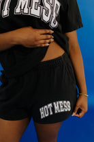 Person wearing a black t-shirt and shorts with 'HOT MESS' text on a blue background