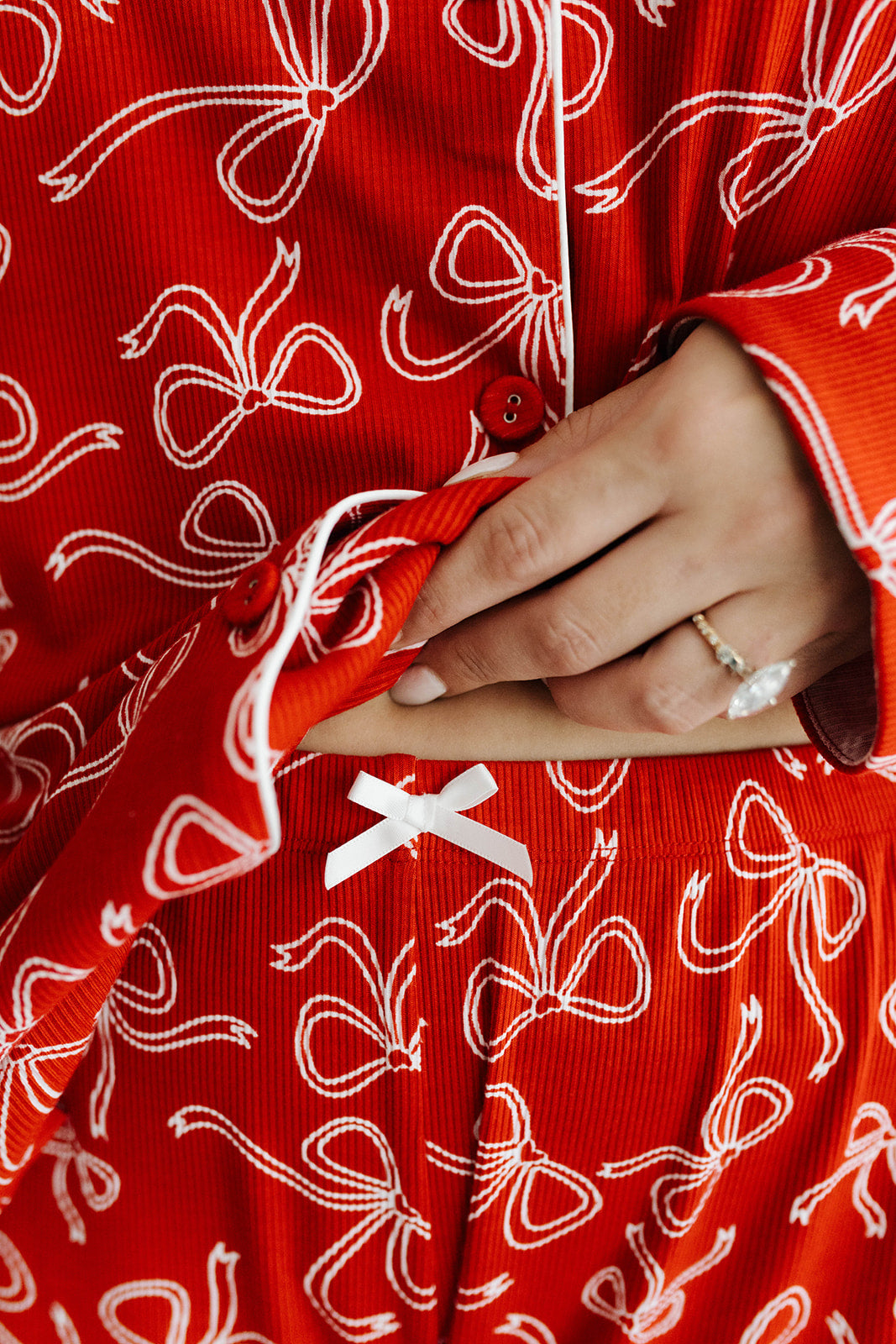 Red bow pajama set with white bow pattern and a hand holding a red fabric piece.