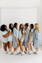 models smiling at each other wearing cloud ruffle pajamas and blue striped robe 