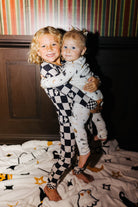 Two young children wearing halloween pjs one holding the other