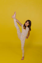 Kolly doing a toe touch on a yellow background