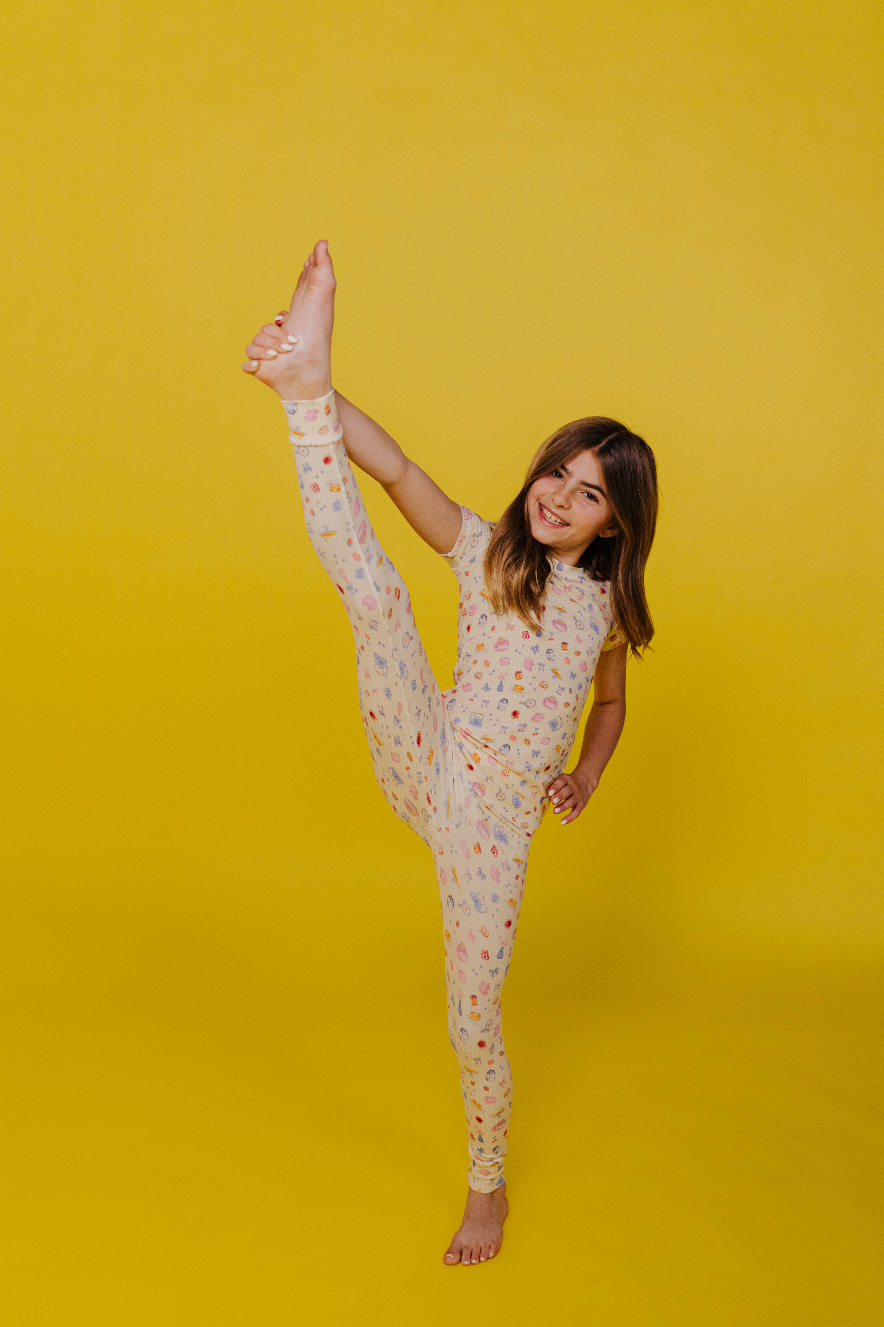 Kolly doing a toe touch on a yellow background