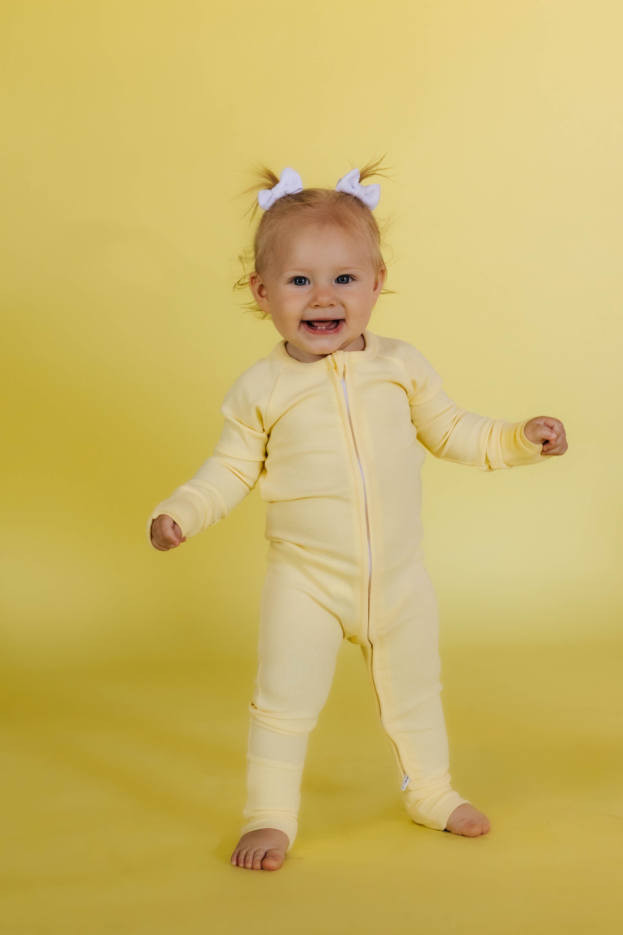 phoebe standing in the butter yellow pjs against a butter yellow background