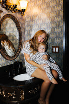 Adult holding a baby in matching leopard pajamas