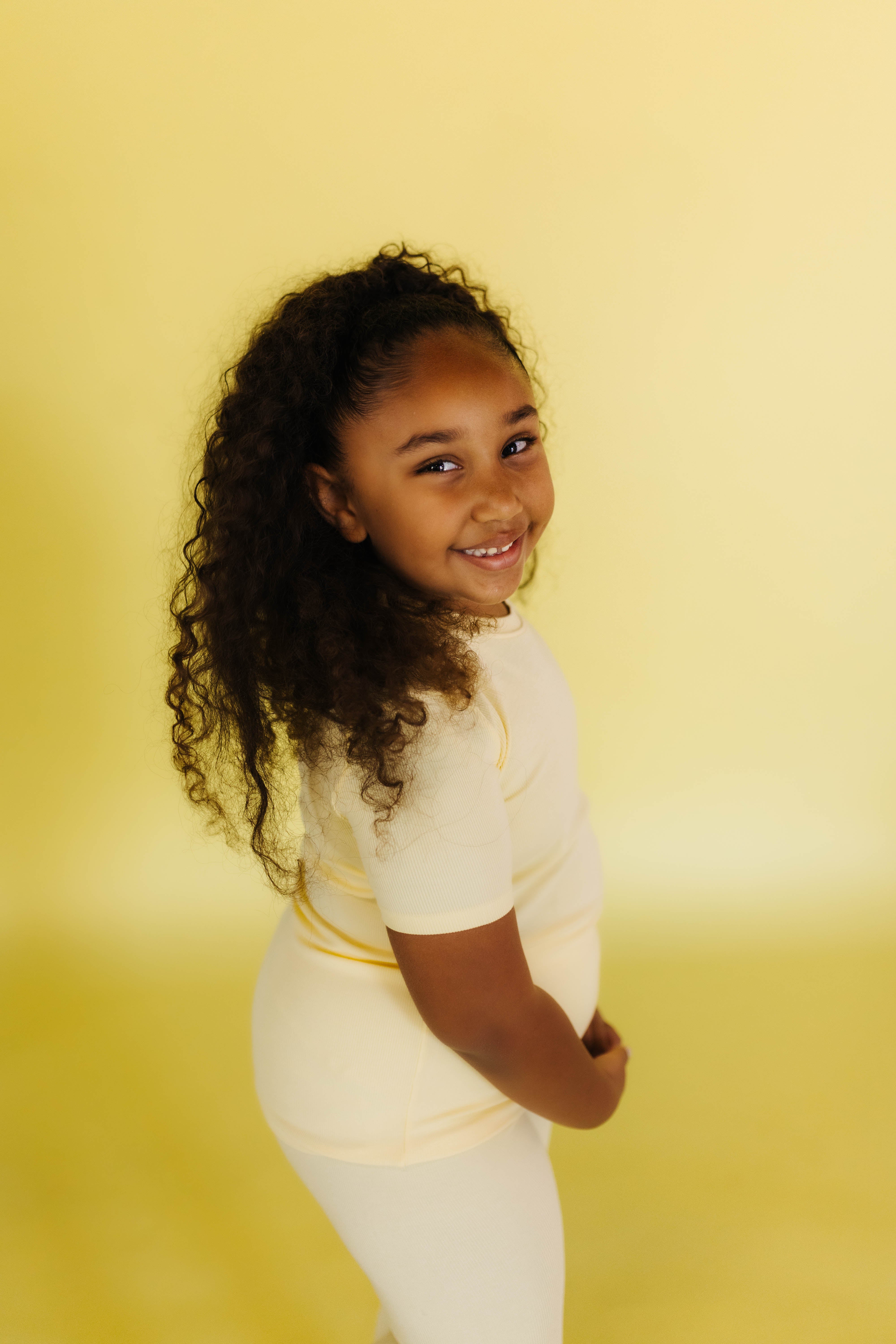 Isla smiling in the yellow pjs against a yellow backdrop