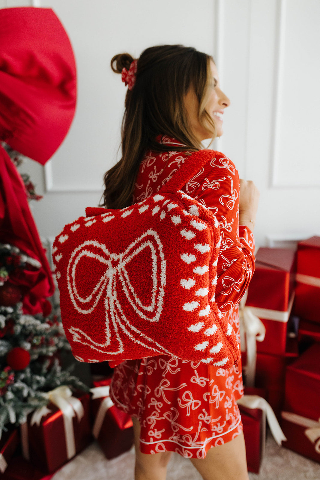 Woman wearing a red bow pajama set in a festive setting with Christmas decorations.