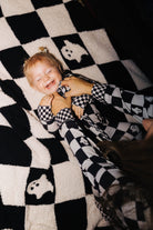 Baby wearing Ghost Check zip pajamas on the matching blanket
