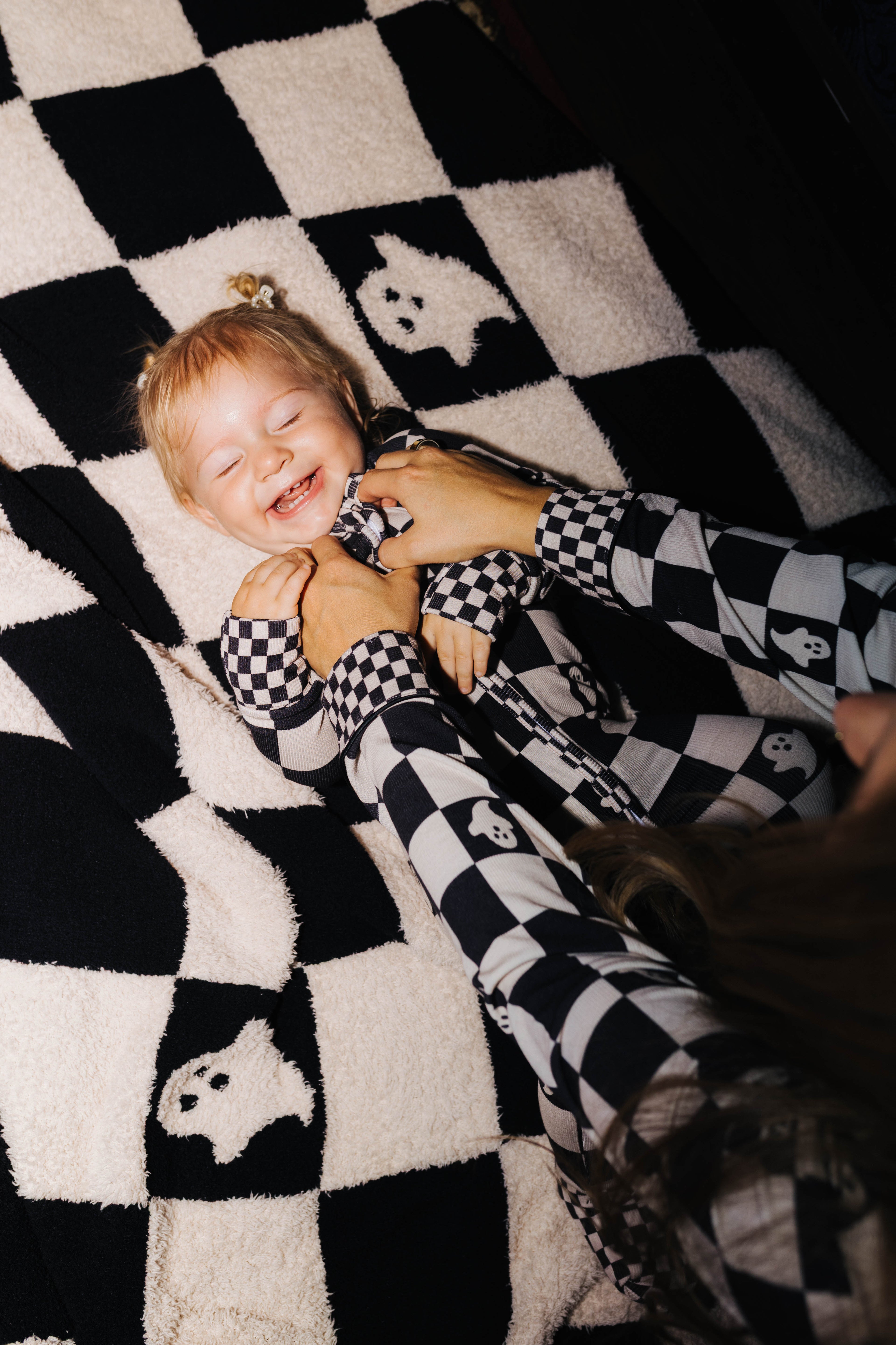 Baby wearing Ghost Check zip pajamas on the matching blanket