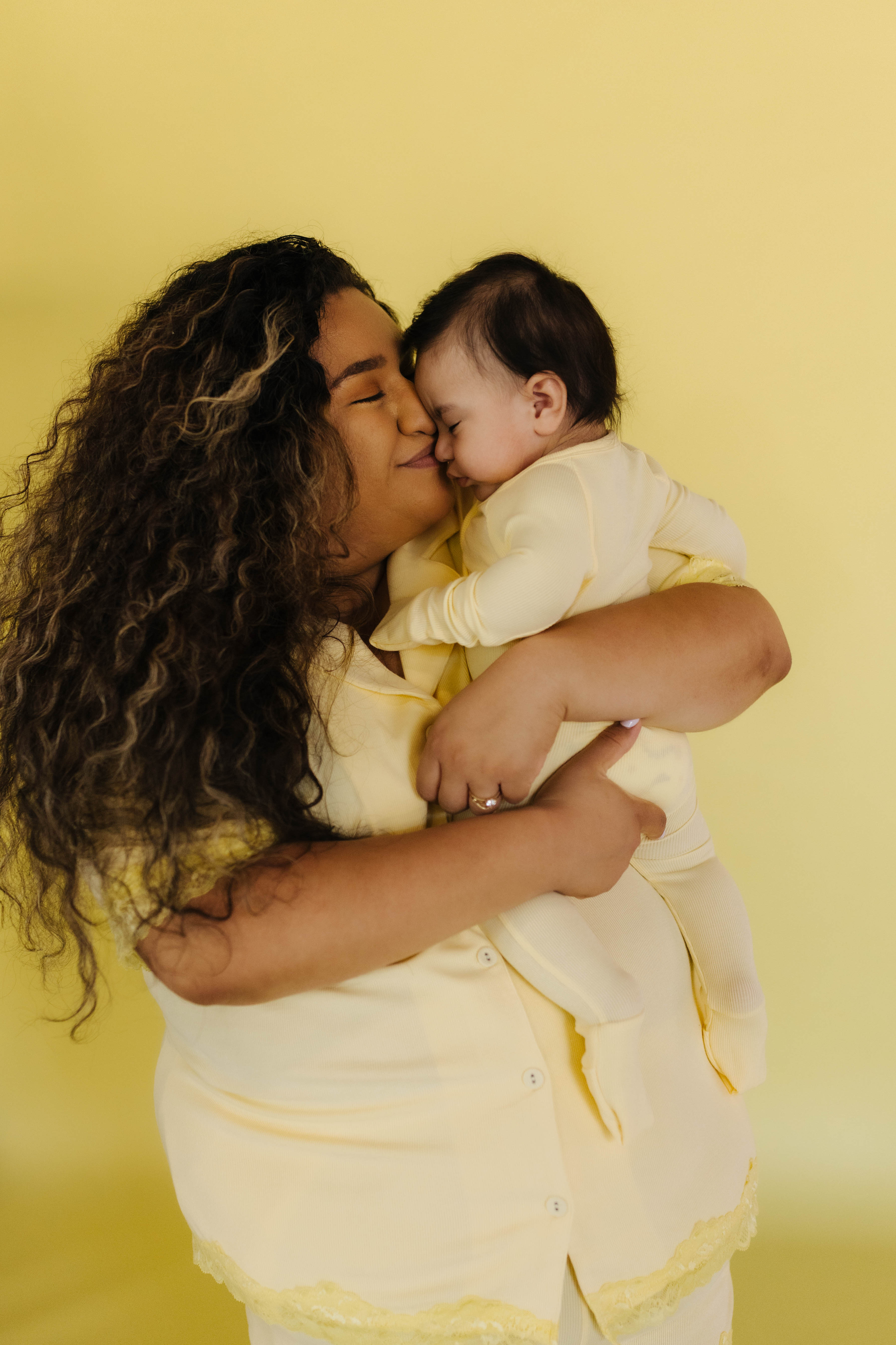perla snuggling her baby in the matching yellow pjs