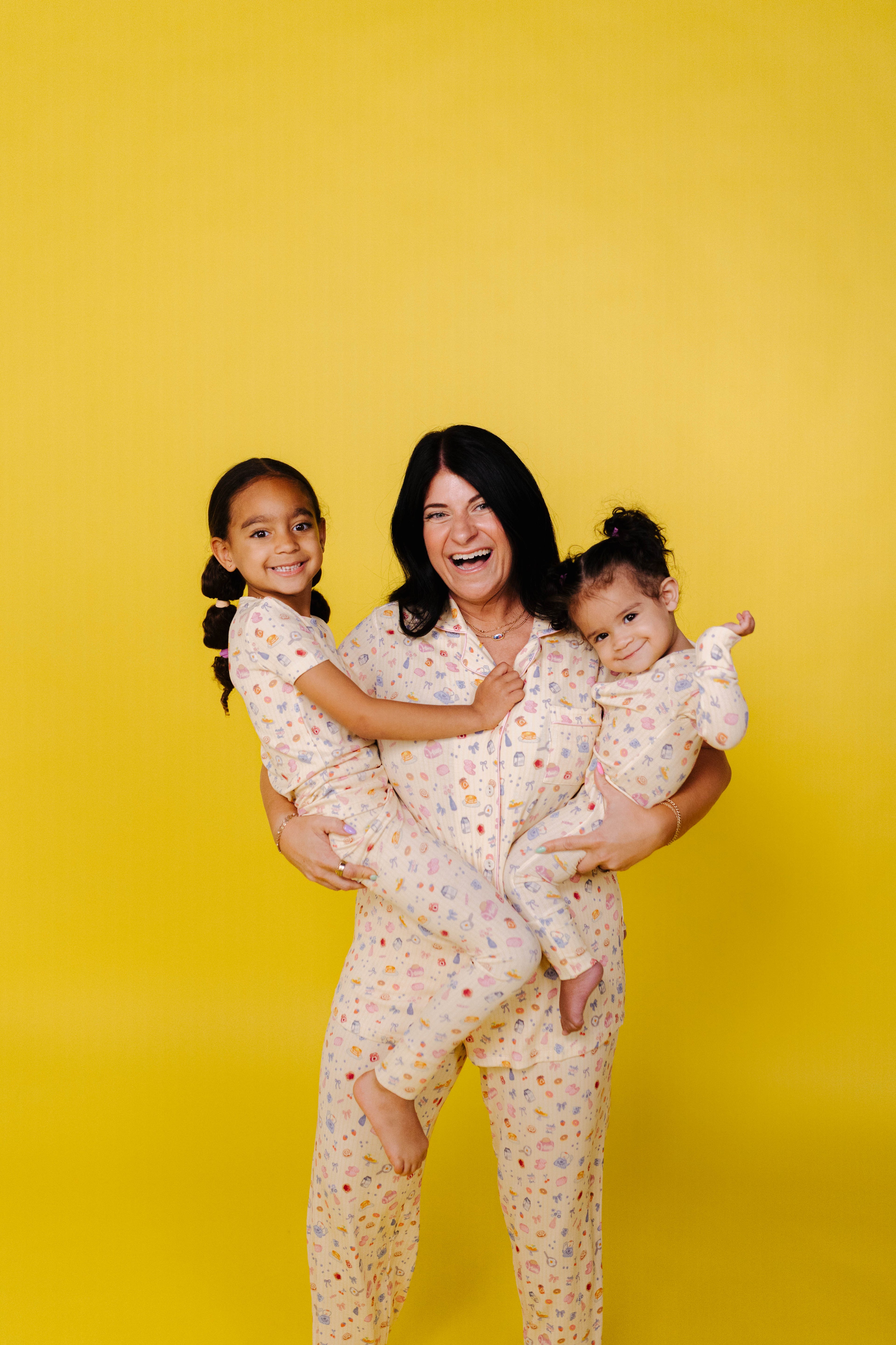 Woman and two children in matching pajamas against a yellow background