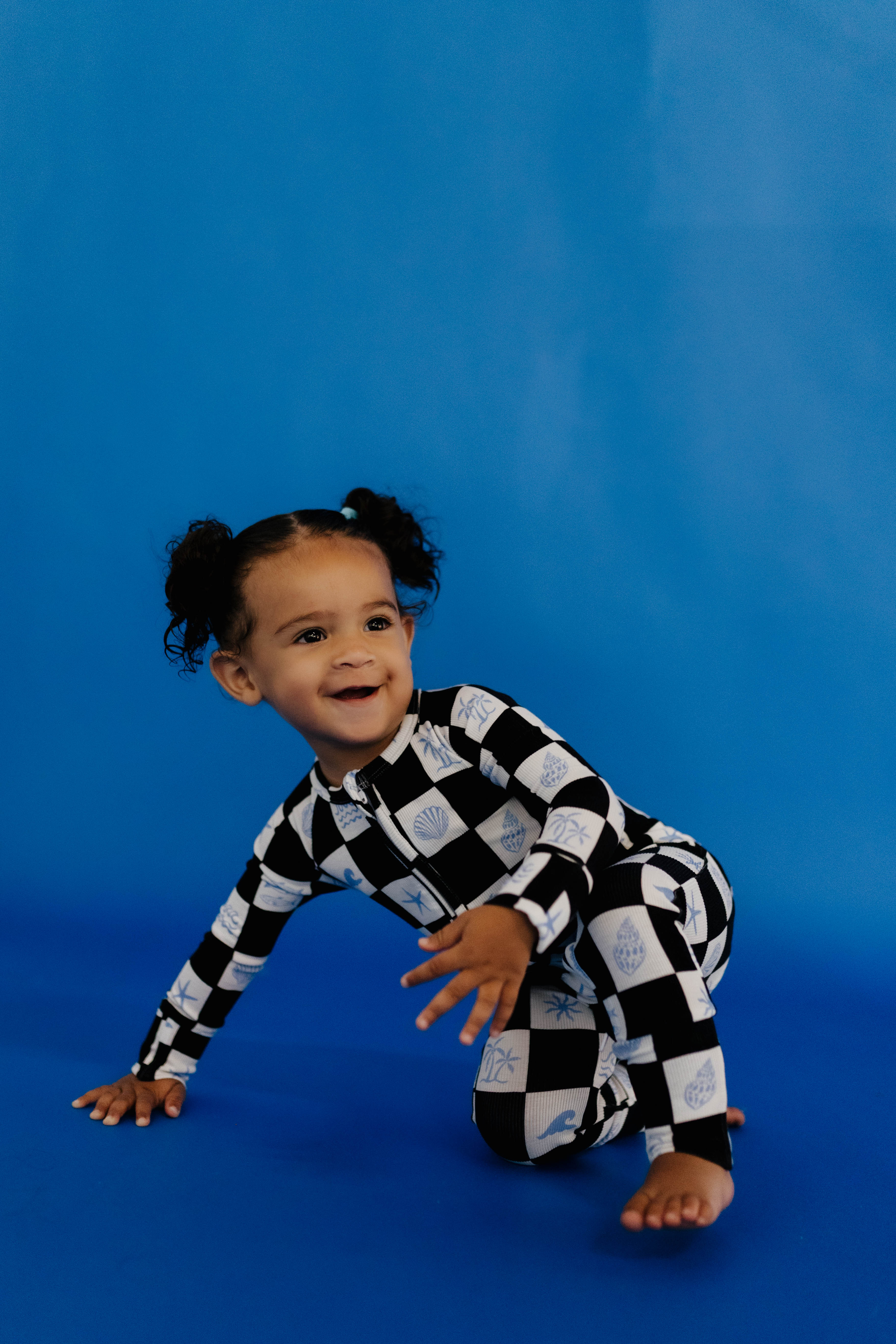 Child wearing a black and white checkered outfit on a blue background size 3-6 months