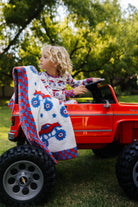 Child playing with a red toy truck outdoors, with the blanket decor