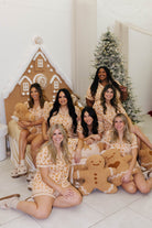 Group of women in matching pajamas with gingerbread theme in a festive setting.