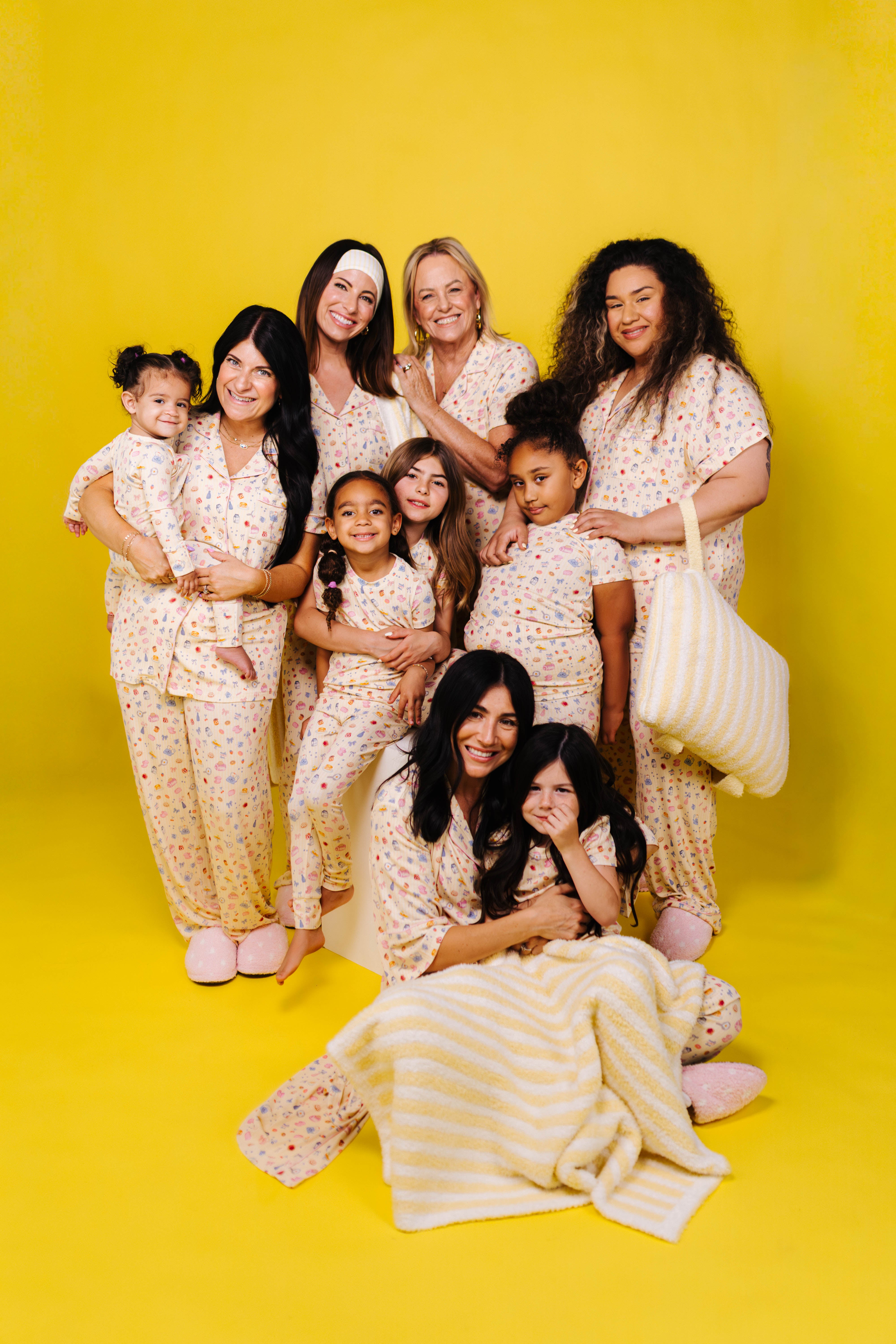 Group of women and children in matching outfits against a yellow background