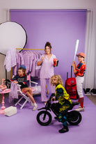 Children in colorful outfits with a woman in a studio setting