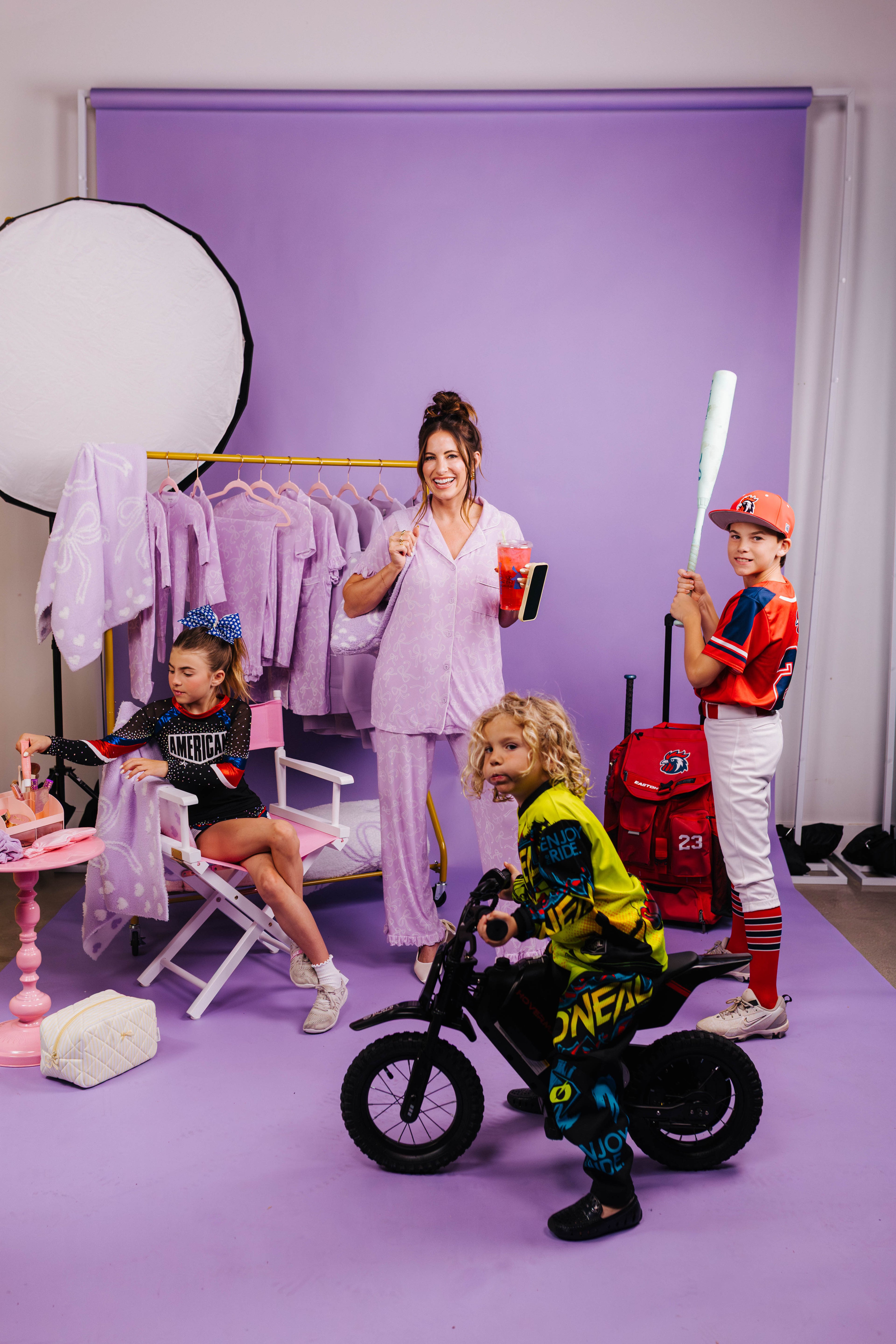 Children in colorful outfits with a woman in a studio setting