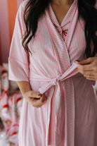 Person wearing a pink and white striped robe with a blurred background