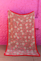Back of the strawberry blanket showing the mostly red/green print held against a pink background