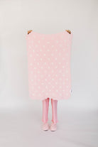 Person holding a pink polka dot blanket with a white background