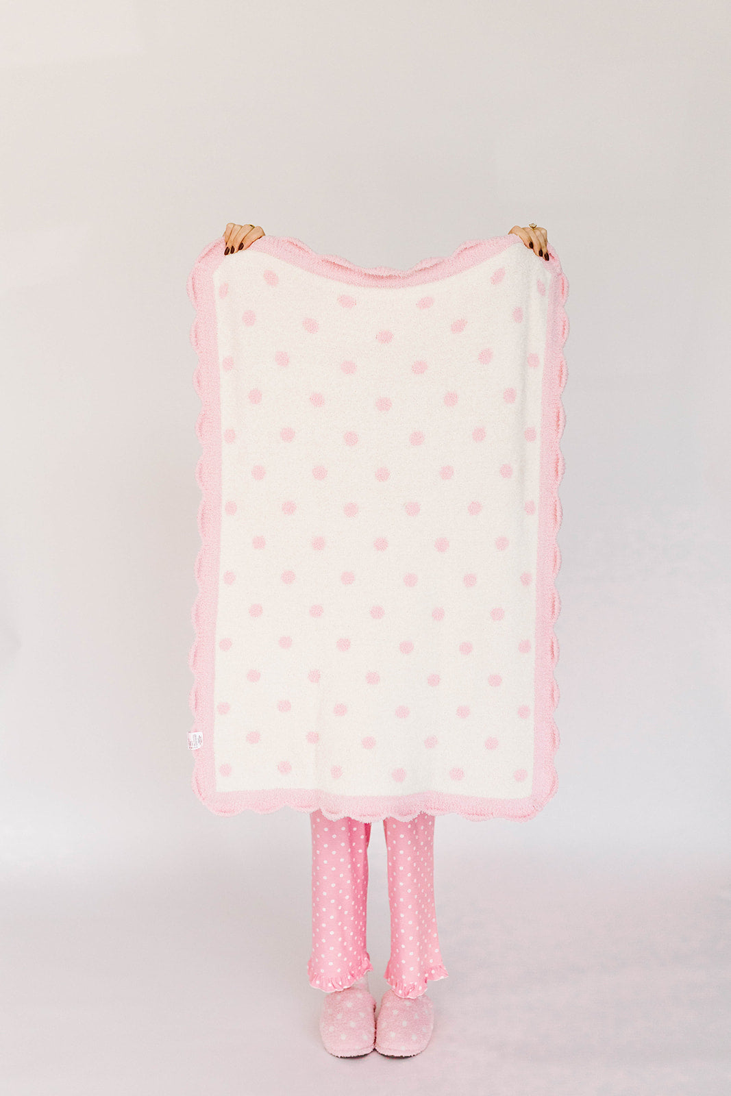 Pink polka dot blanket with matching tights on a white background
