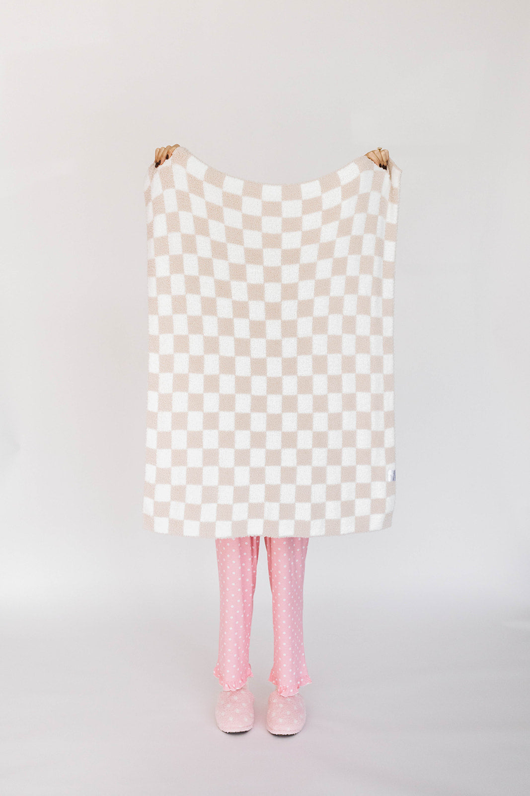 Checkered blanket with pink tights and shoes on a plain background