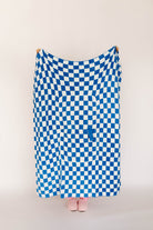 Blue and white checkered blanket draped over a person on a plain background
